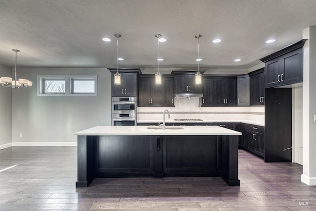 kitchen with backsplash, white gas stovetop, sink, decorative light fixtures, and hardwood / wood-style flooring