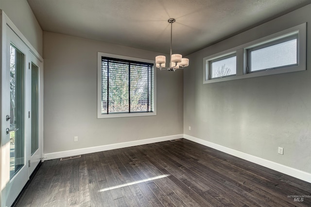 unfurnished room with a chandelier and dark wood-type flooring