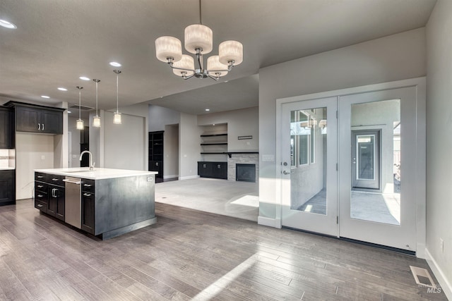 kitchen featuring sink, hardwood / wood-style flooring, an island with sink, decorative light fixtures, and a chandelier