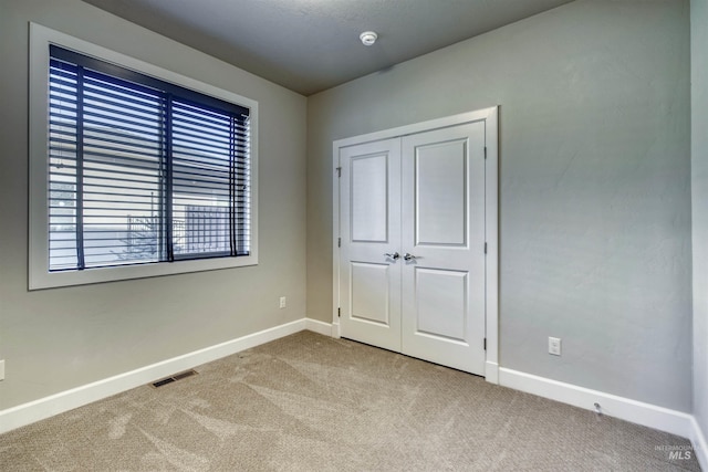 unfurnished bedroom featuring light colored carpet and a closet