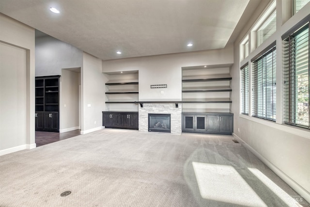 unfurnished living room with a fireplace, carpet floors, and built in features