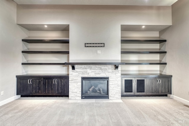 unfurnished living room featuring a stone fireplace and light colored carpet