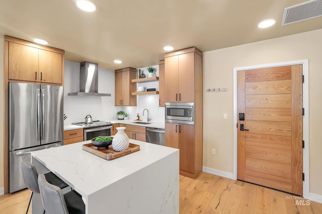 kitchen featuring visible vents, wall chimney exhaust hood, stainless steel appliances, open shelves, and a sink