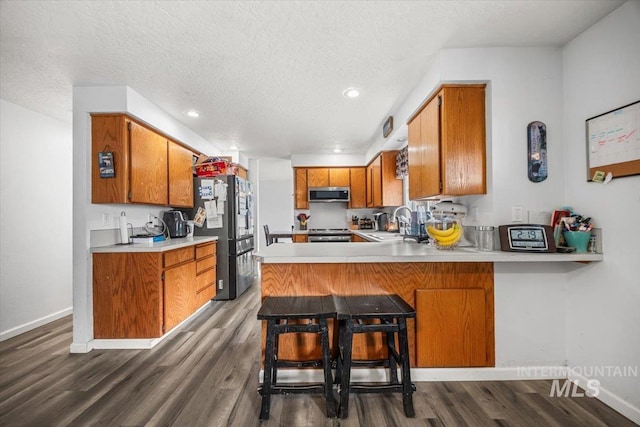 408 Tanoak Cir, Nampa, ID 83686 - kitchen featuring a sink, brown cabinets, stainless steel microwave, dark wood-style floors, and freestanding refrigerator