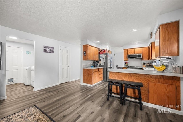 408 Tanoak Cir, Nampa, ID 83686 - kitchen with brown cabinets, light countertops, dark wood-style floors, and stainless steel appliances