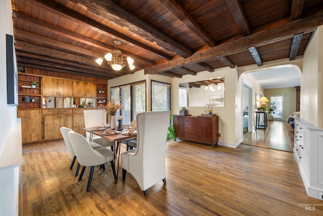 dining area featuring wood finished floors, arched walkways, a chandelier, beamed ceiling, and wood ceiling