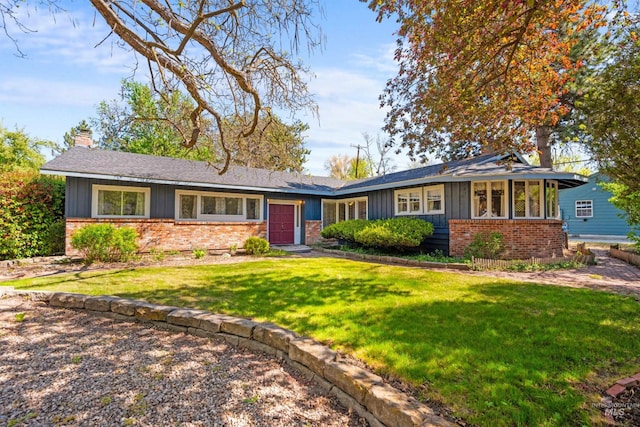 single story home featuring board and batten siding, an attached garage, brick siding, and a front yard