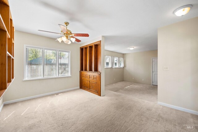 unfurnished living room with carpet flooring, ceiling fan, and baseboards