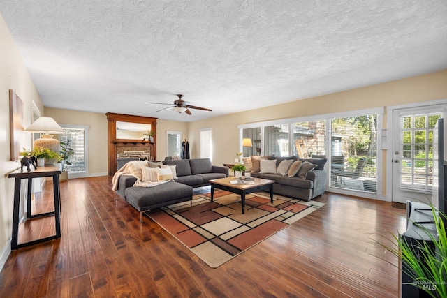 living area featuring dark wood-style floors, a textured ceiling, ceiling fan, and baseboards