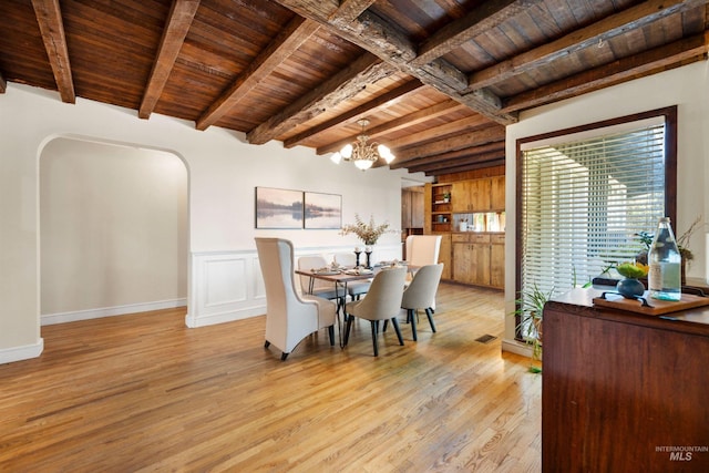 dining space featuring wooden ceiling, arched walkways, light wood finished floors, beam ceiling, and a chandelier