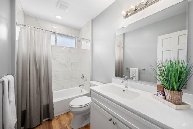 bathroom featuring toilet, wood finished floors, vanity, and shower / tub combo with curtain
