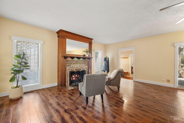 living room with a fireplace, dark wood-style flooring, and healthy amount of natural light