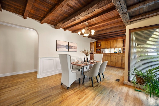 dining area featuring wooden ceiling, beam ceiling, light wood-style floors, a chandelier, and arched walkways