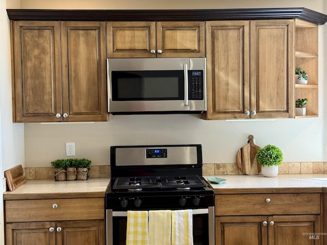 kitchen with stainless steel appliances, light countertops, open shelves, and brown cabinetry