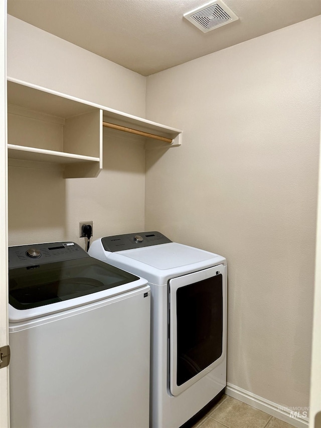 washroom with washer and dryer, light tile patterned floors, and baseboards