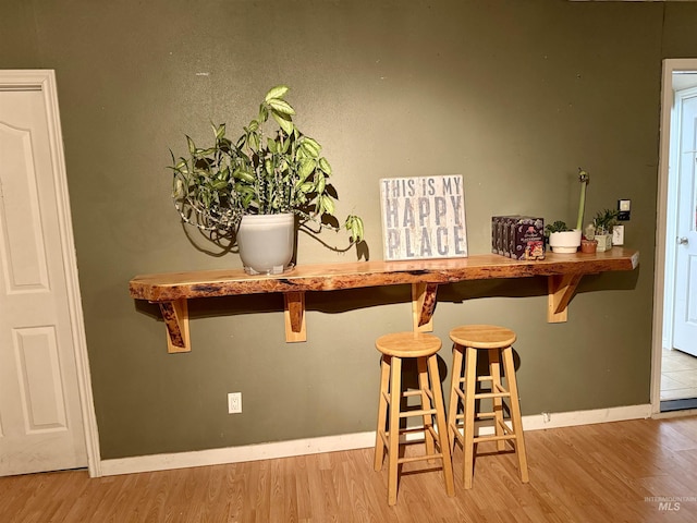 bar area featuring wood finished floors and baseboards