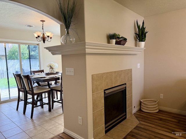 dining room with a chandelier, baseboards, a fireplace, light wood-style floors, and arched walkways
