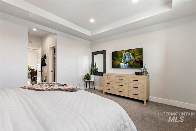 bedroom with a tray ceiling and light colored carpet