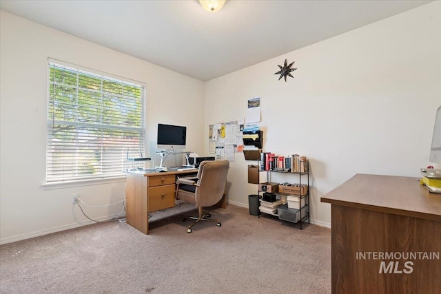 office space featuring light carpet, plenty of natural light, and baseboards