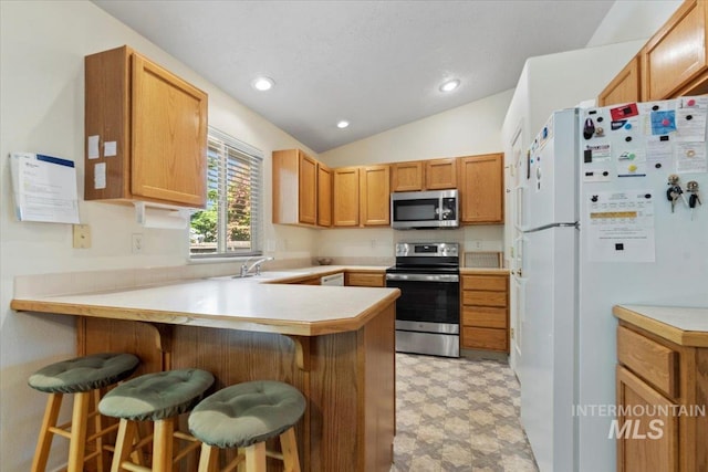 kitchen featuring stainless steel appliances, a peninsula, light floors, lofted ceiling, and light countertops