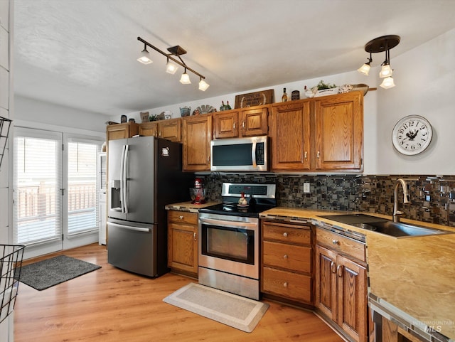 kitchen featuring stainless steel appliances, sink, pendant lighting, and light hardwood / wood-style floors