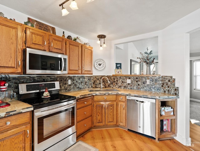 kitchen featuring appliances with stainless steel finishes, sink, backsplash, and light wood-type flooring