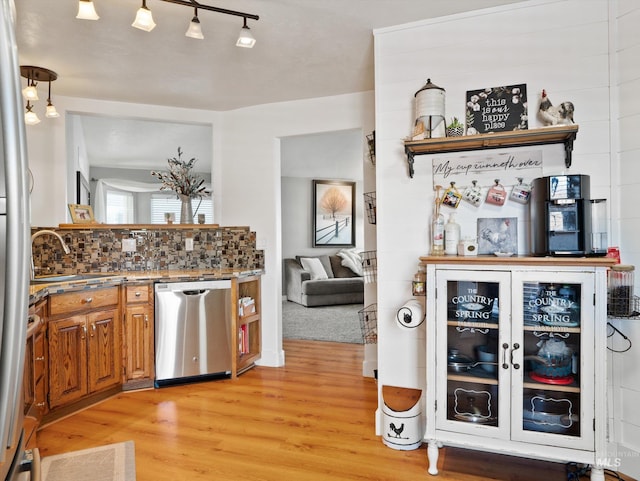 kitchen with tasteful backsplash, stainless steel dishwasher, and light hardwood / wood-style flooring