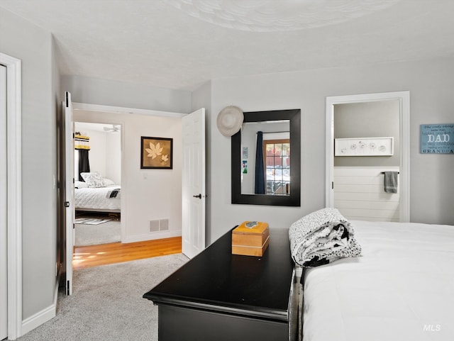 bedroom featuring ensuite bath and light carpet