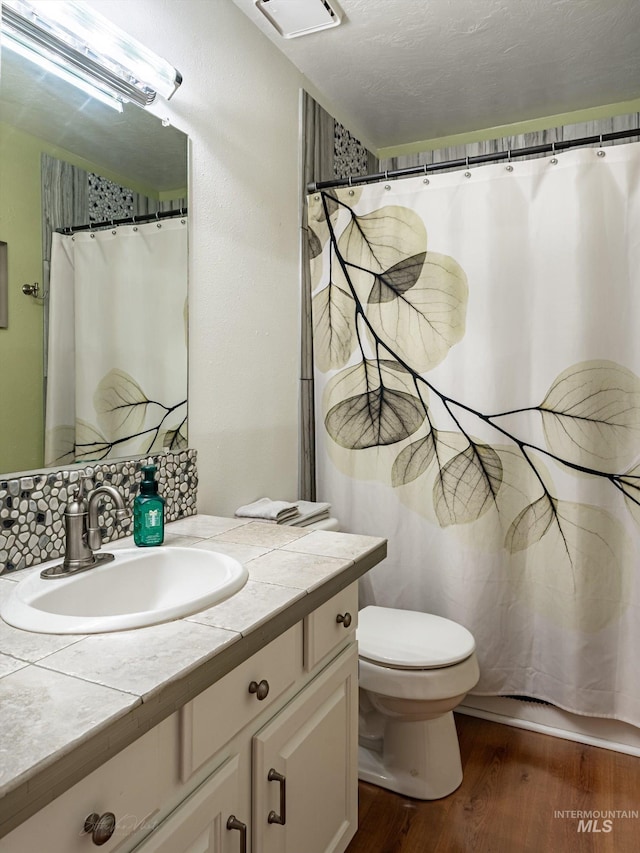 bathroom featuring toilet, a shower with curtain, wood-type flooring, a textured ceiling, and vanity