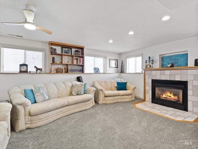 carpeted living room featuring a tiled fireplace and a textured ceiling