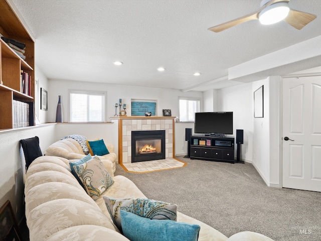 carpeted living room with ceiling fan, a fireplace, and a textured ceiling