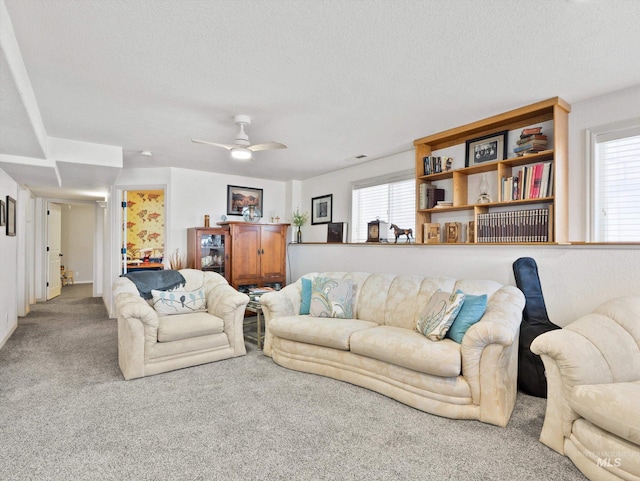 carpeted living room featuring ceiling fan and a textured ceiling