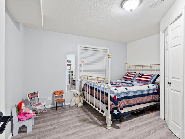 bedroom with a textured ceiling and light wood-type flooring