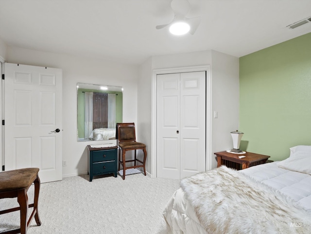 bedroom featuring light colored carpet, ceiling fan, and a closet