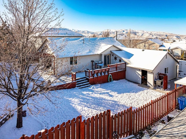 snow covered house with a deck with mountain view