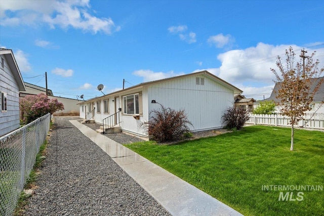 view of property exterior with a lawn, entry steps, and a fenced backyard