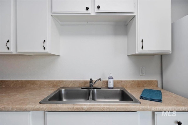 kitchen featuring a sink, white cabinets, and light countertops