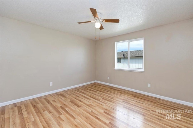 spare room with a ceiling fan, baseboards, light wood-style flooring, and a textured ceiling