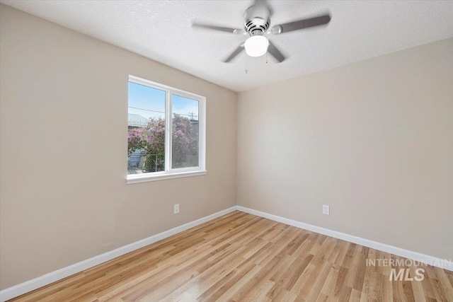 empty room with baseboards, a ceiling fan, and light wood finished floors