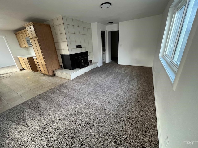 unfurnished living room with baseboards, light colored carpet, and light tile patterned flooring