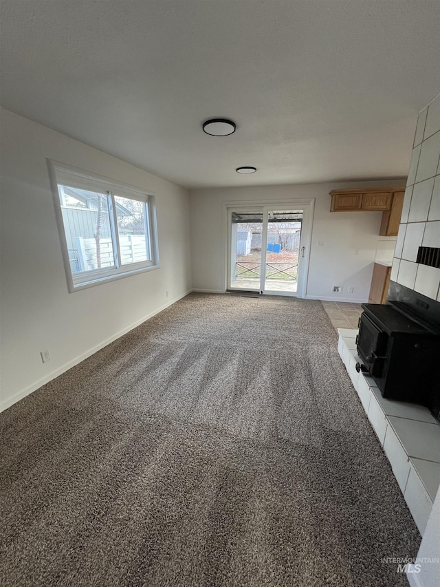 unfurnished living room featuring baseboards, a wealth of natural light, and light carpet