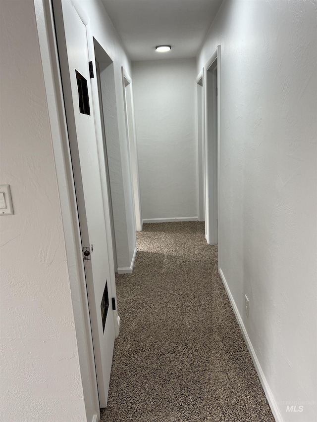 hallway featuring carpet flooring and baseboards