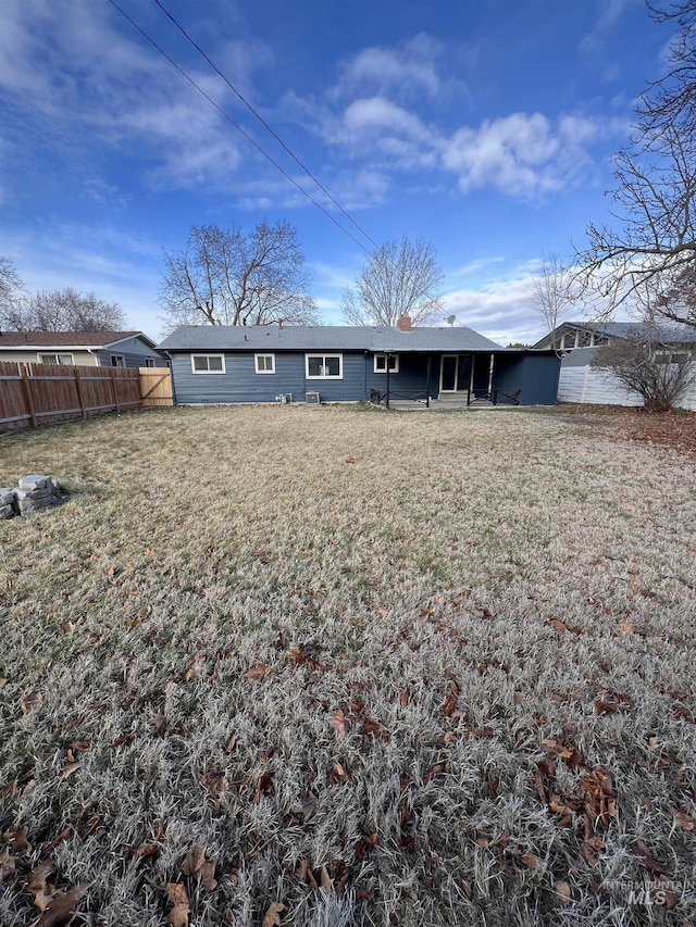 rear view of property with fence and a lawn