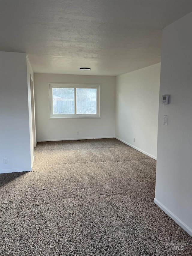 carpeted empty room with a textured ceiling and baseboards