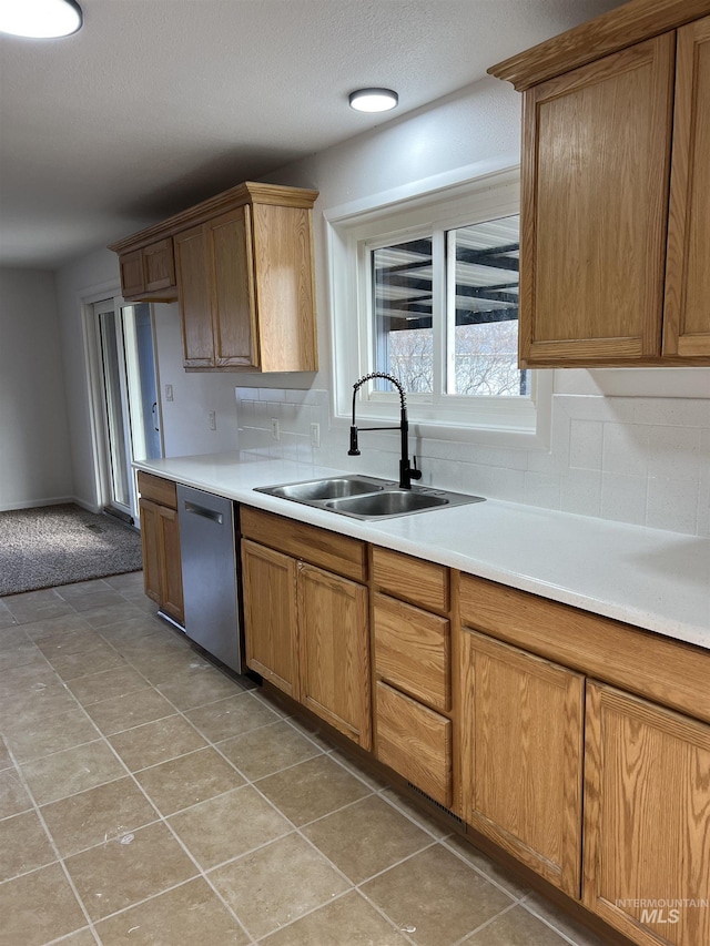 kitchen featuring dishwasher, decorative backsplash, light countertops, and a sink