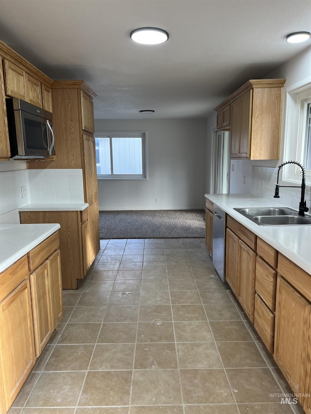 kitchen with a sink, stainless steel appliances, light tile patterned flooring, and light countertops