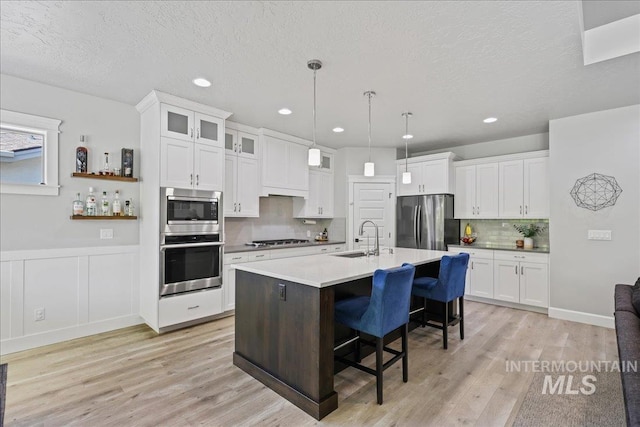 1753 S Kimball Way, Boise, ID 83709 - kitchen with appliances with stainless steel finishes, a sink, a breakfast bar, white cabinetry, and light wood finished floors
