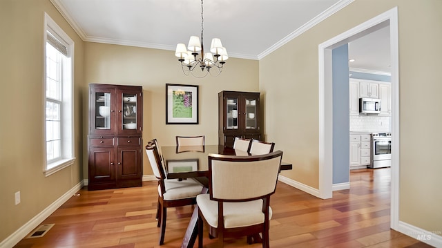 dining space with ornamental molding, light wood-type flooring, visible vents, and baseboards