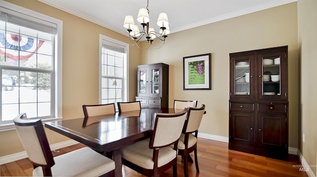 dining space featuring light wood-type flooring, an inviting chandelier, baseboards, and crown molding