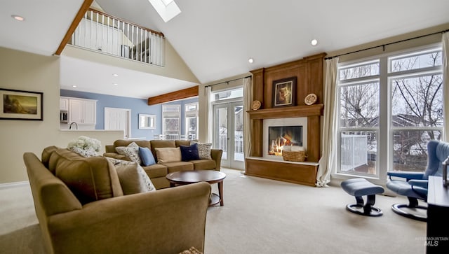 living area featuring a skylight, recessed lighting, light colored carpet, a large fireplace, and high vaulted ceiling